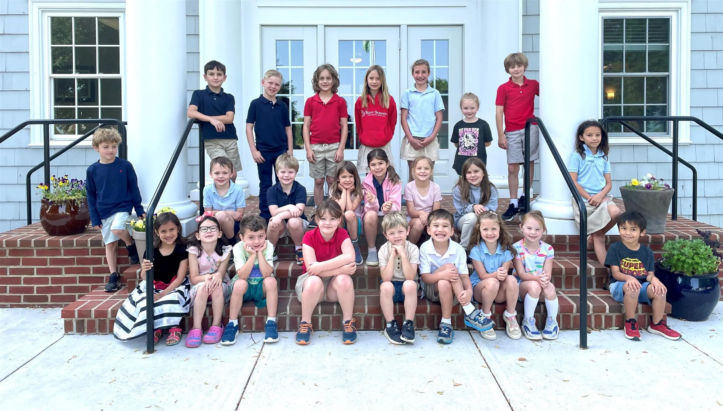 Group of Kent School students smiling at the camera sitting together on the front steps