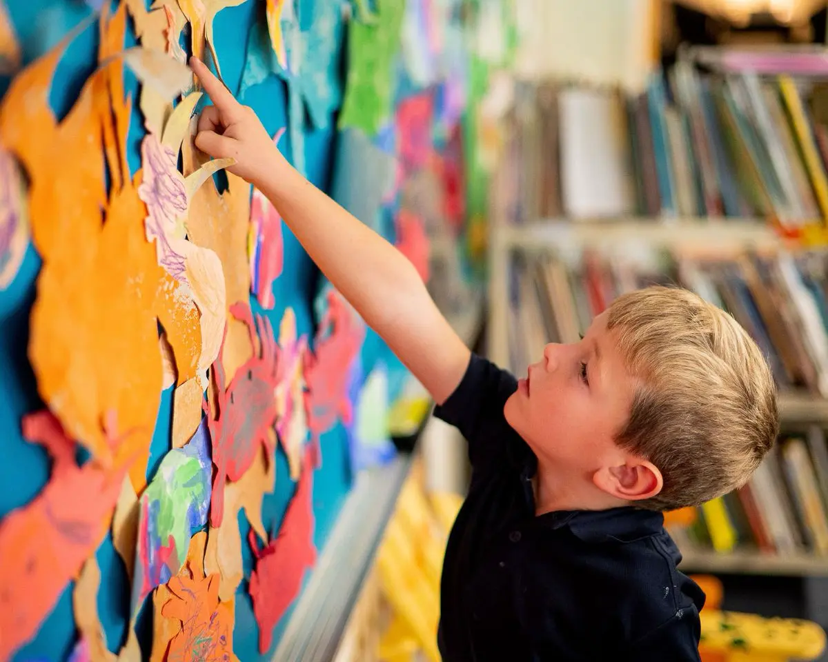 Little School student pointing to his artwork